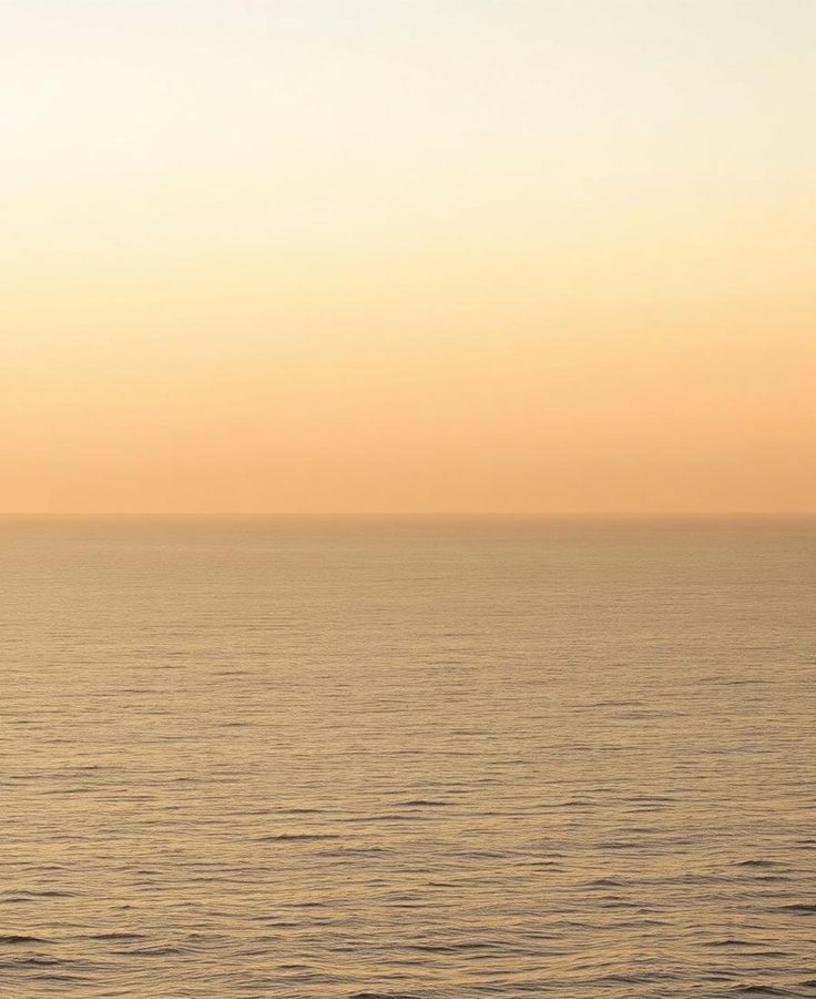 A calm sea under a hazy golden sky